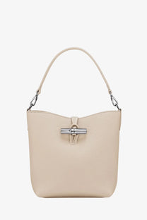Longchamp women’s le roseau beige leather bucket bag with silver-tone clasp and matching handle in white background