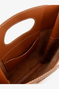 A tan leather tote bag with smooth supple texture and white stitching from Loro Piana women’s just bag collection tart
