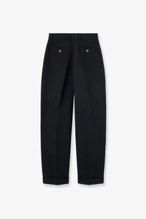 Back view of black tailored trousers with gold button details on pockets in loro piana womens cale linen and cotton style