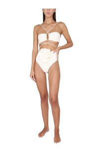 White one-piece swimsuit with crisscross straps and large floral embellishment on hip by magda butrym