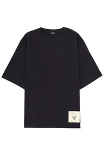 Black oversized crewneck t-shirt with cream-colored embroidered patch and Maison Margiela men’s silver necklace