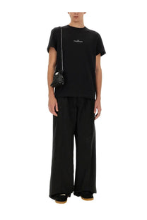 Black leather mini bag with silver chain strap and white logo detail paired with maison margiela multicolor cotton shirt