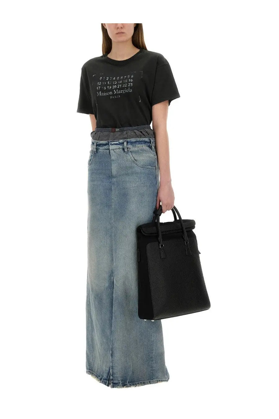 Black leather tote bag with top handle and flap closure shown with Maison Margiela women’s denim skirt blue lining