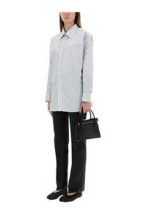 Black textured leather mini handbag with top handle and tassel details complementing maison margiela blue striped cotton shirt