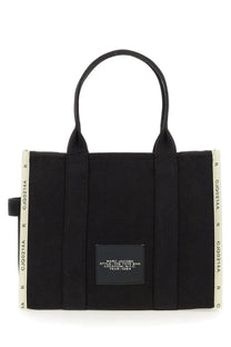 Black canvas marc jacobs tote bag with cream ribbed side panels and a black rectangular brand label in n.y.c