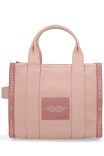 A blush pink canvas tote bag with matching handles and a rectangular leather patch embossed with marc jacobs text