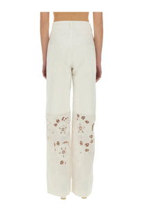 Cream-colored wide-leg upcycled linen trousers with delicate brown floral embroidery on lower legs by Marine Serre