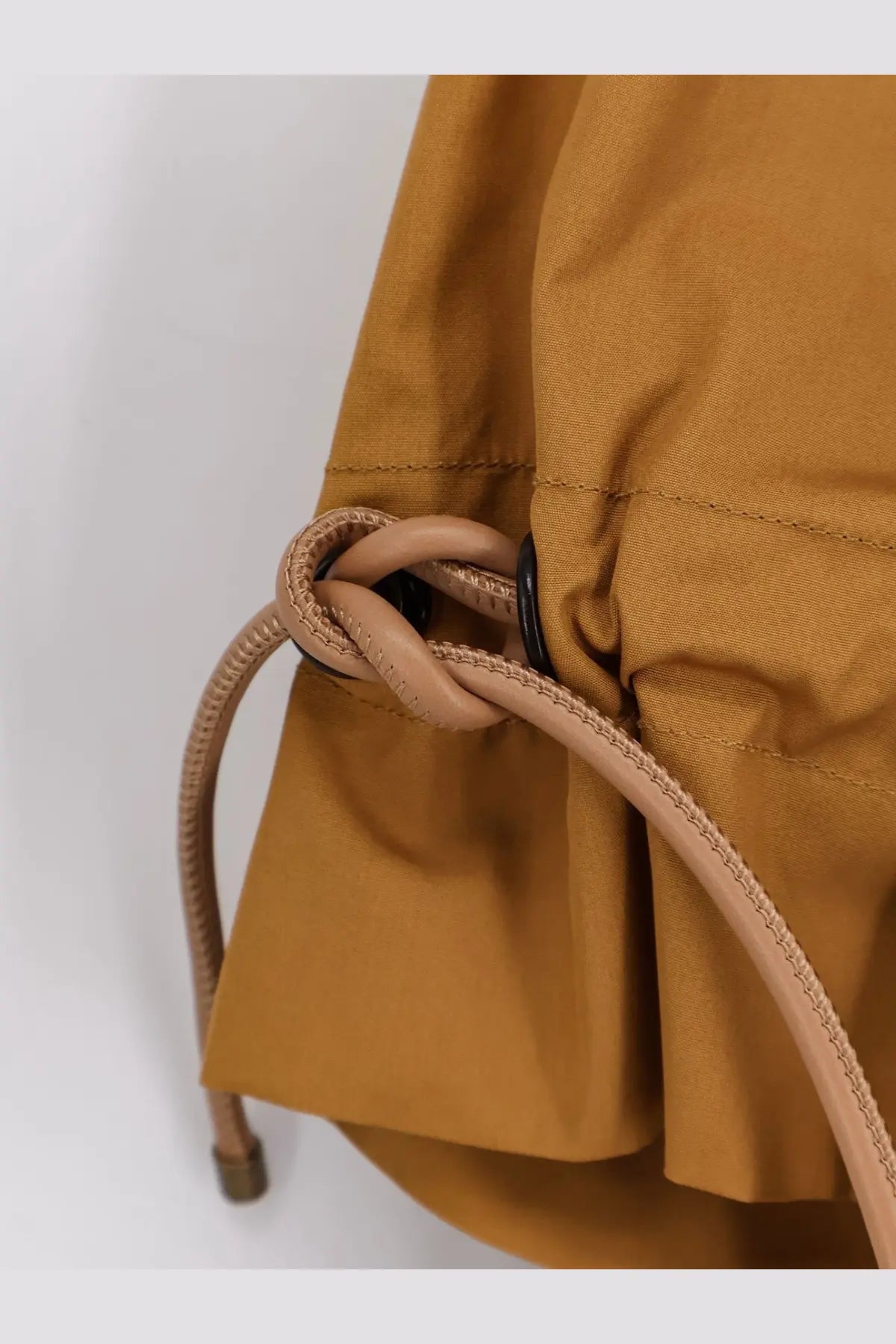 Tan woven drawstring tied in a knot on mustard yellow cotton fabric bag of max mara mxmadorni shirt terra