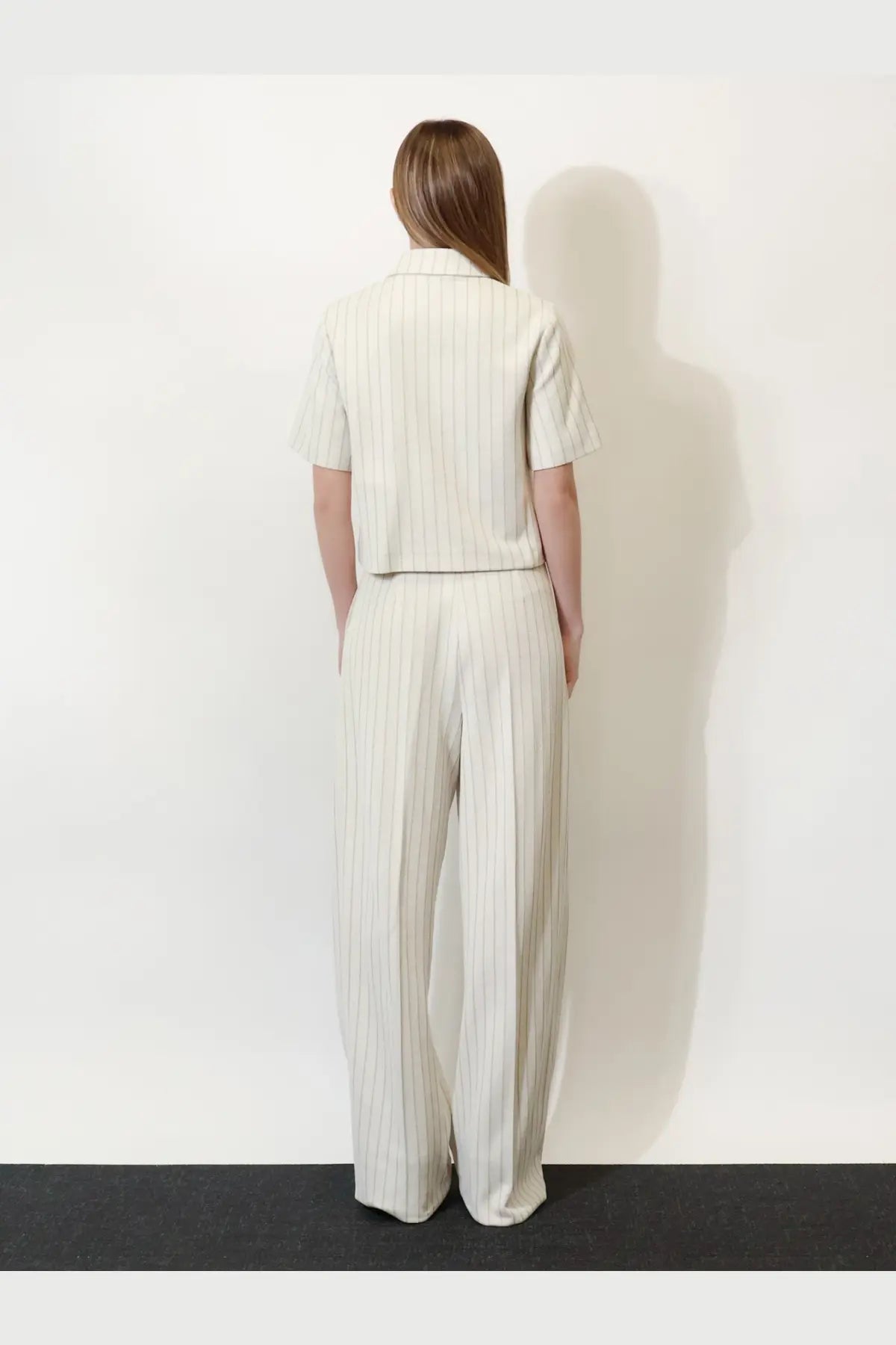 A woman wears a cream striped short-sleeved shirt and wide-leg trousers in a max mara mxmangio cotton blazer white set