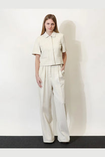 A woman wears a Max Mara women’s mxmangio cotton blazer in off-white with thin vertical gray pinstripes