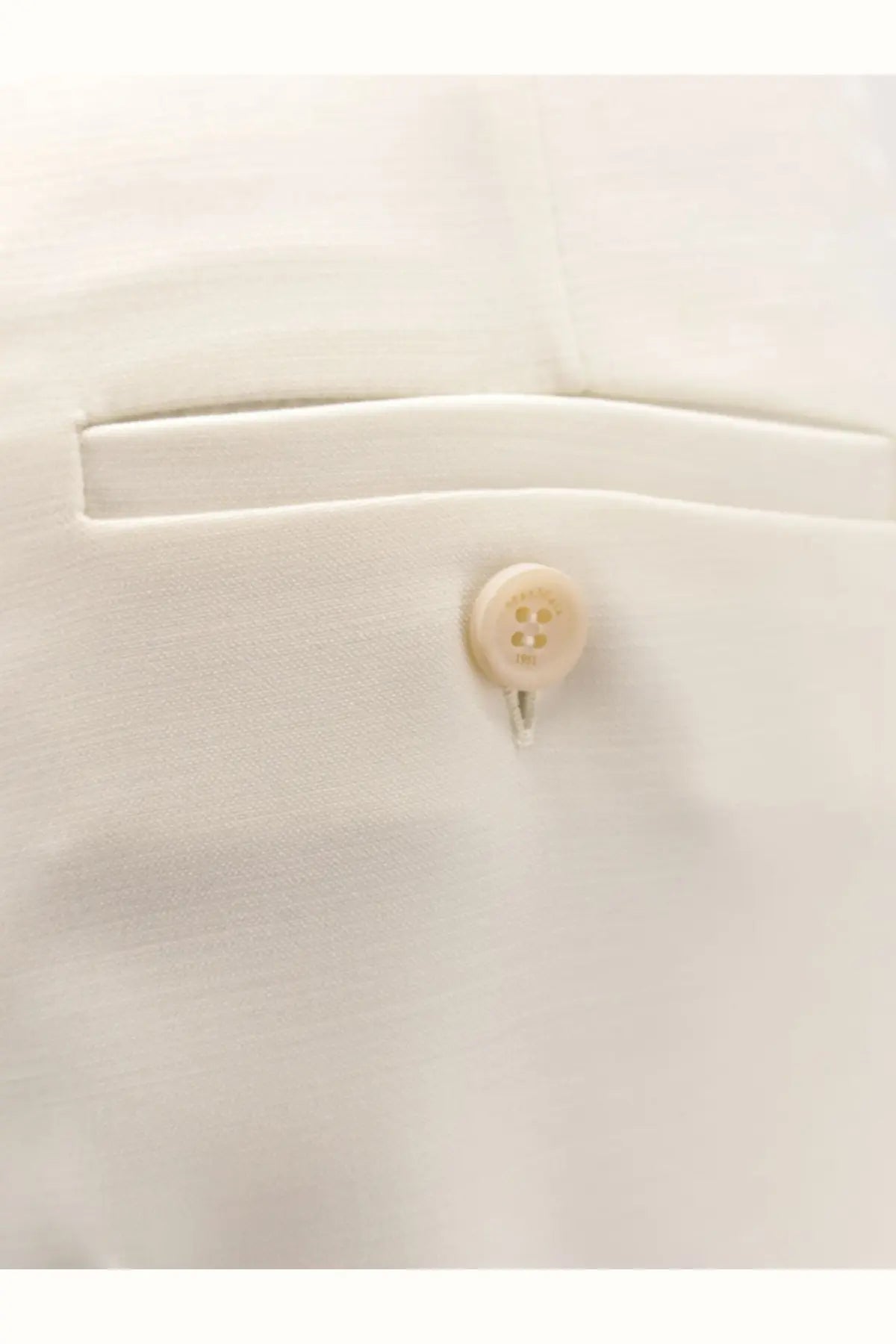 A cream-colored round button with four holes and a metallic shank on max mara women’s mxmrugiada virgin wool trousers white
