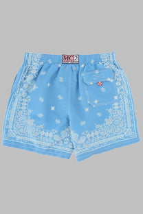 Light blue Mc2 Saint Barth men’s swim trunks with white bandana paisley floral print and red cross patch on pocket