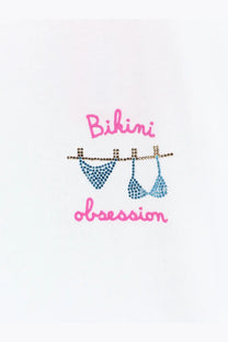 Blue rhinestone-embellished bikini tops hanging on a gold-rhinestone clothesline with pink cursive text bikini obsession