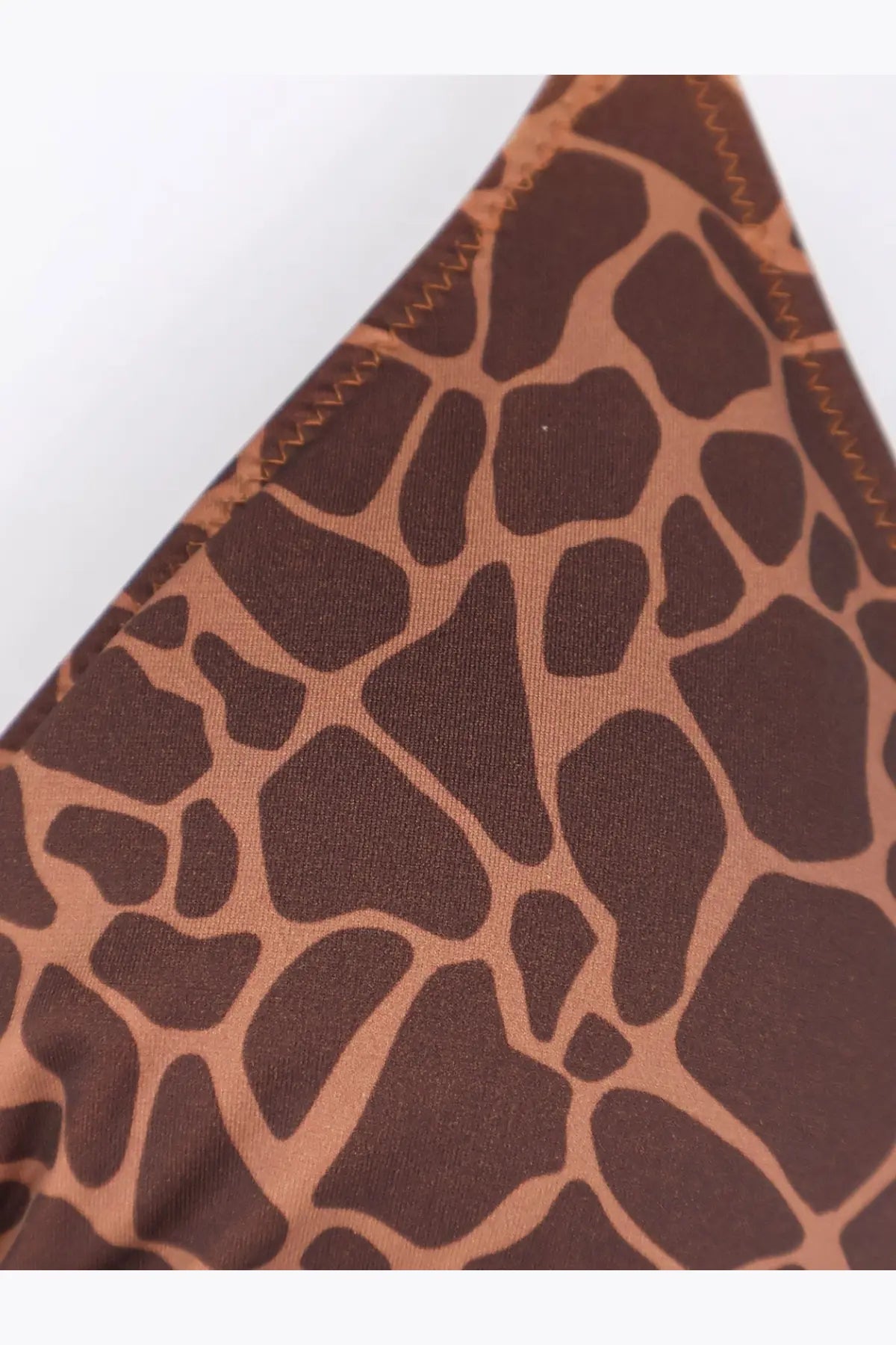 Close-up of brown and tan giraffeskin print nylon fabric with zigzag stitching on mc2 saint barth women’s leah bikini top
