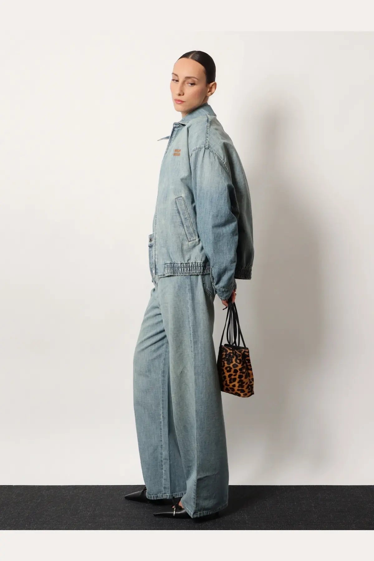 Miu Miu women’s brown animal print leather crossbody bag paired with a light-wash denim jacket with subtle stitching