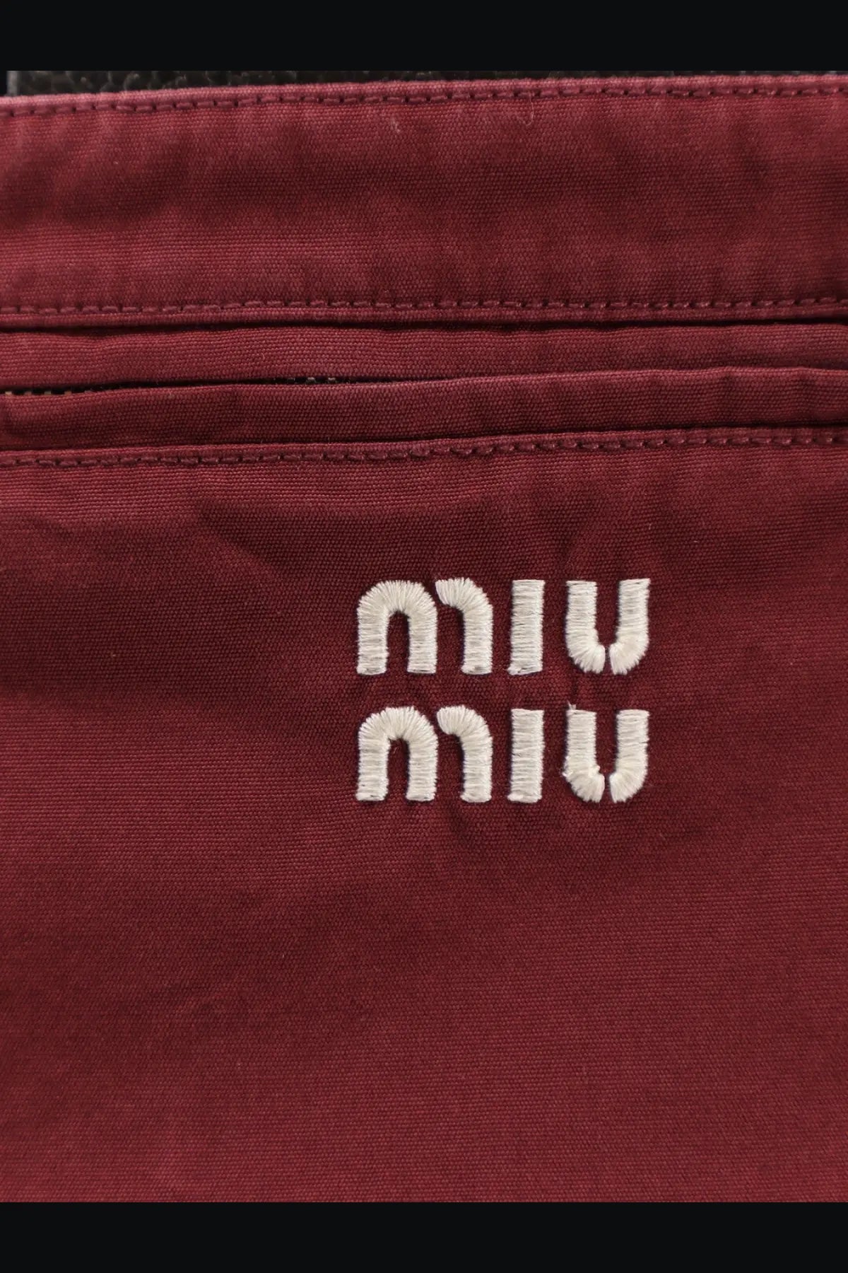 A burgundy canvas crossbody bag with white embroidered Miu Miu logo featured with Miu Miu women’s cotton mini skirt red