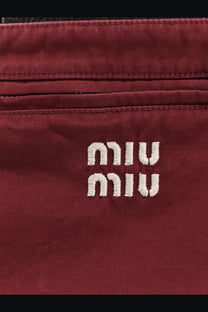A burgundy canvas crossbody bag with white embroidered Miu Miu logo featured with Miu Miu women’s cotton mini skirt red
