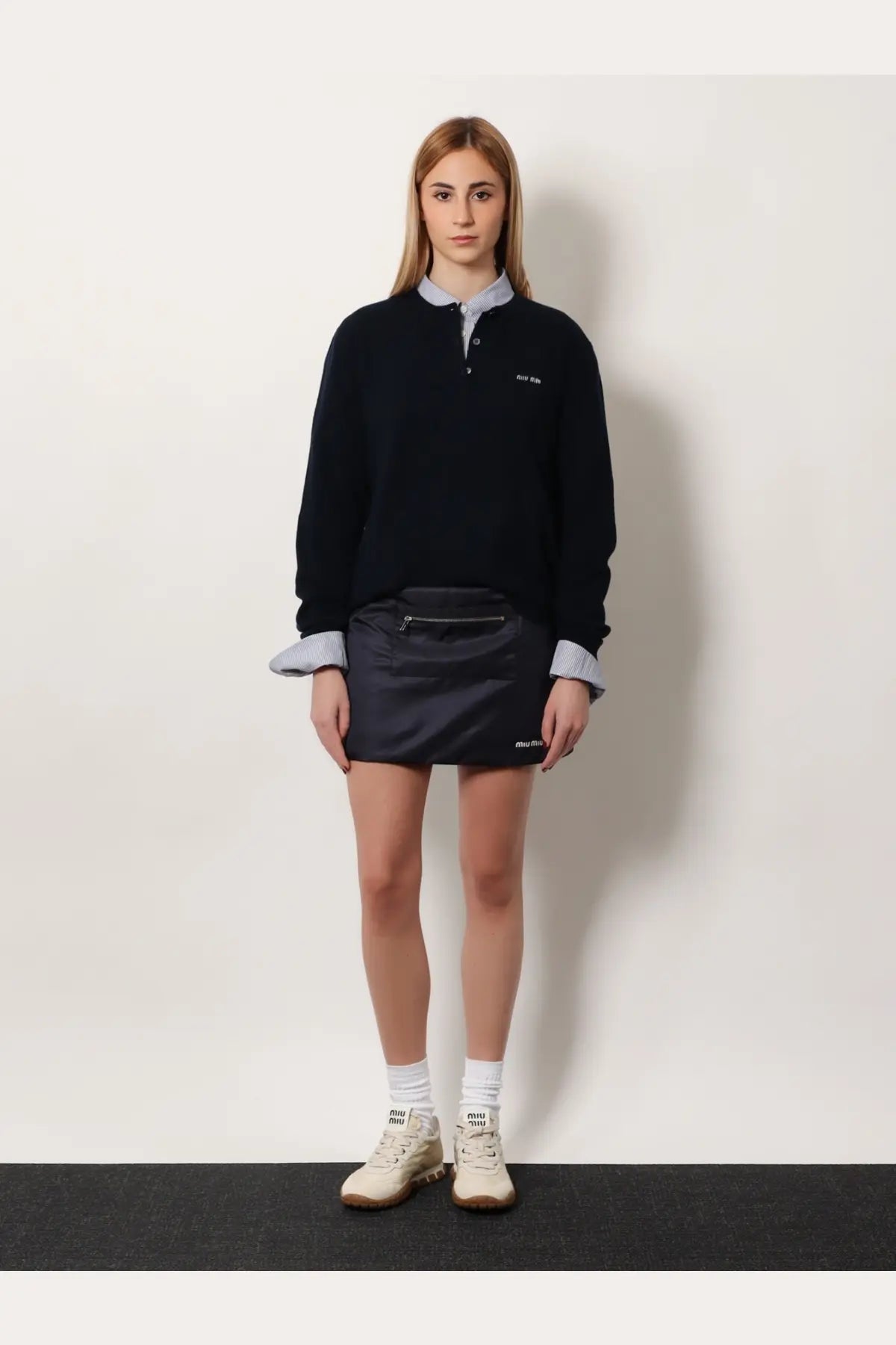 Black miu miu mini skirt with front zipper and brand logo on side paired with blue pin check cotton shirt
