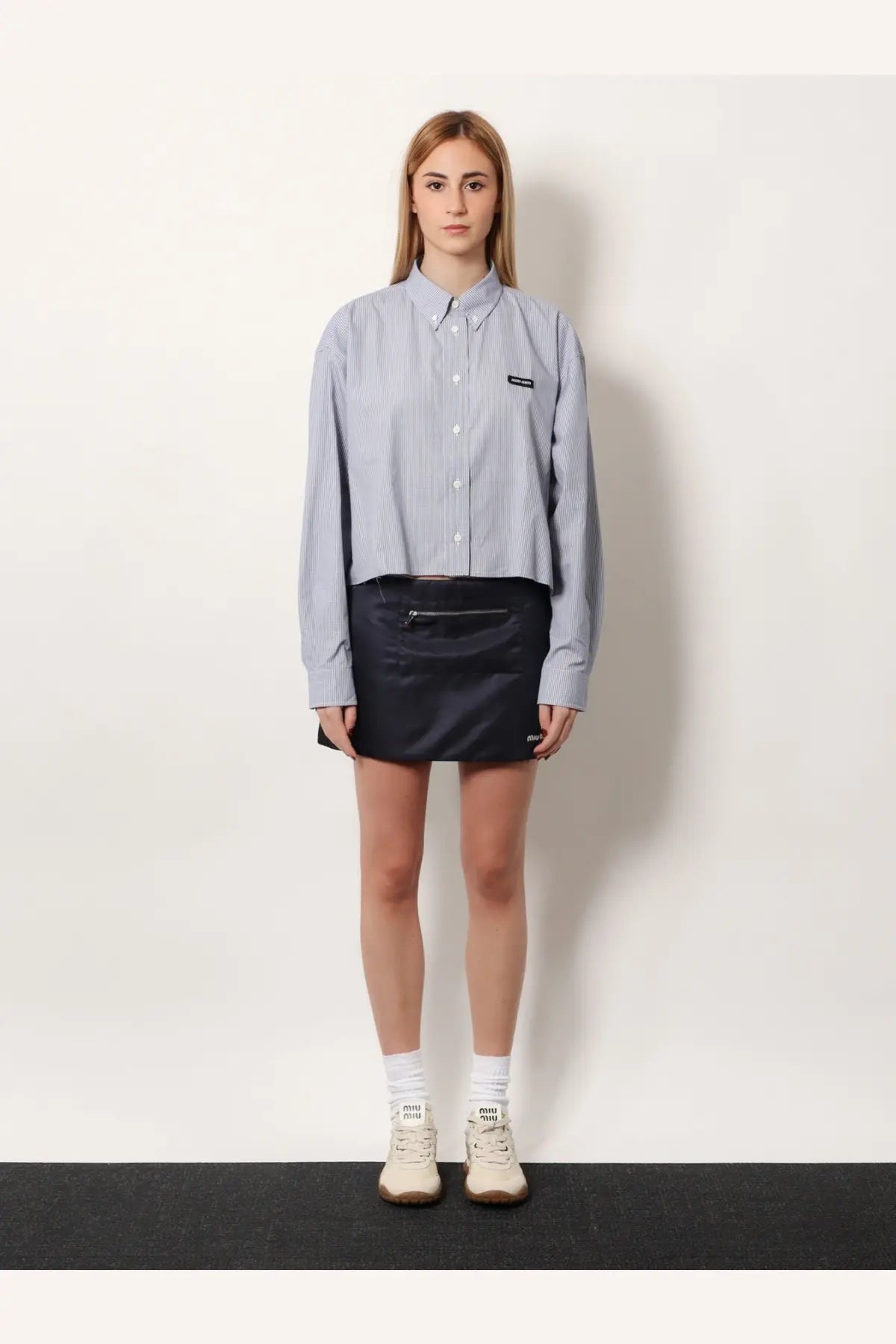 Miu Miu women’s pin check cotton shirt in blue features light blue and white vertical stripes with a black logo patch