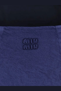 Deep blue denim fabric with textured weave and embossed miu miu logo on miu miu women’s short denim dress inchiostro