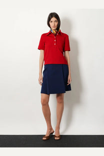 Miu Miu women’s skirt baltico shown with a red short-sleeved polo shirt with white buttons and a colorful patterned collar