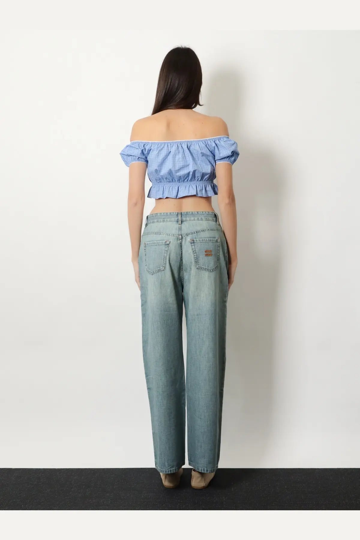 Light-wash denim jeans with relaxed wide-leg cut and subtle distressing paired with miu miu blue striped cotton top