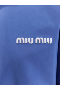 Blue miu miu logo patch with white raised lettering on textured fabric of a purple women’s technical fabric jacket