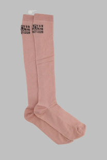 A pair of soft pink ribbed knee-high cotton socks with black maison margiela branding on the cuff
