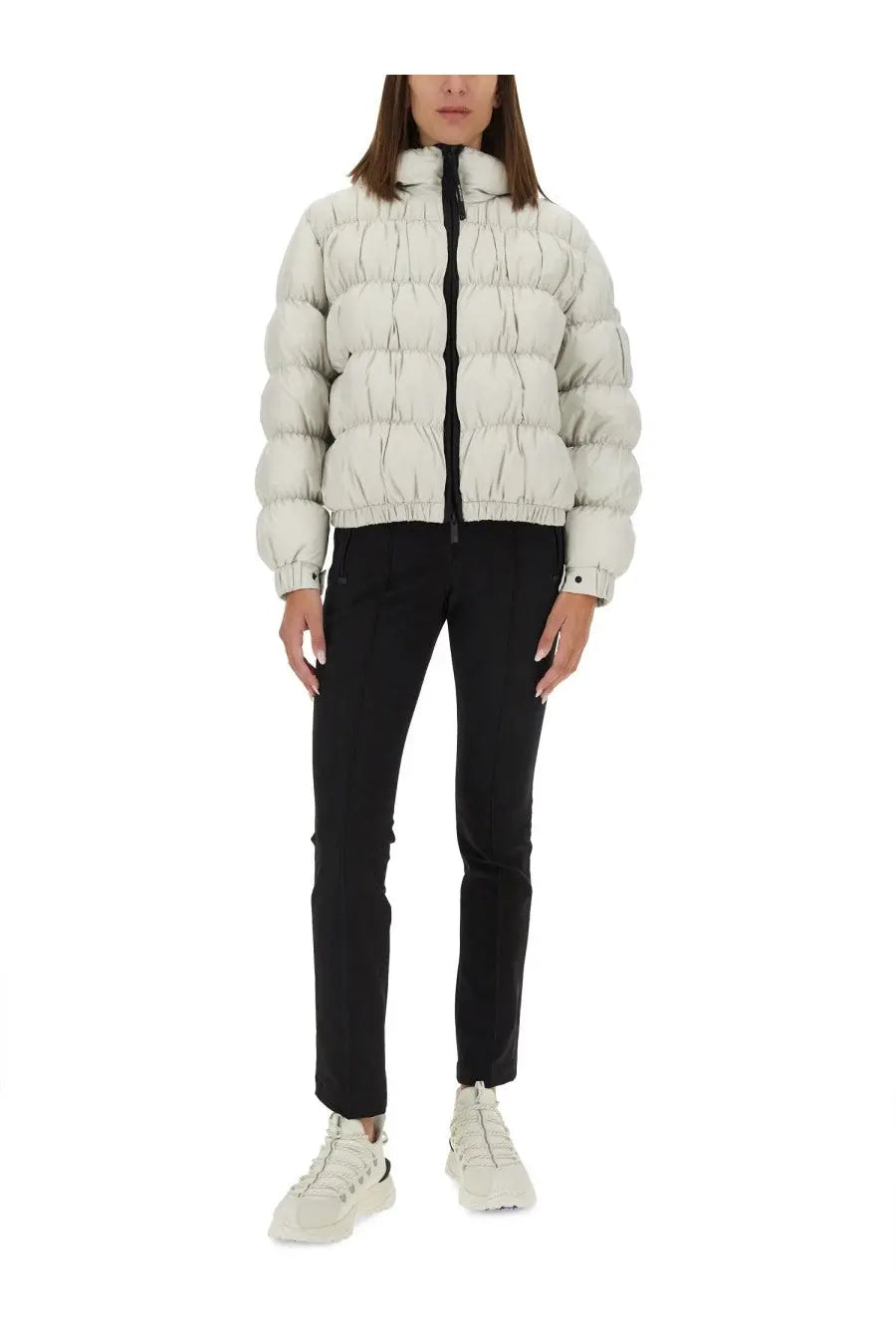 A puffy off-white quilted down jacket with a high collar and black zipper paired with Moncler Grenoble women’s black pants