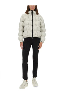 A puffy off-white quilted down jacket with a high collar and black zipper paired with Moncler Grenoble women’s black pants