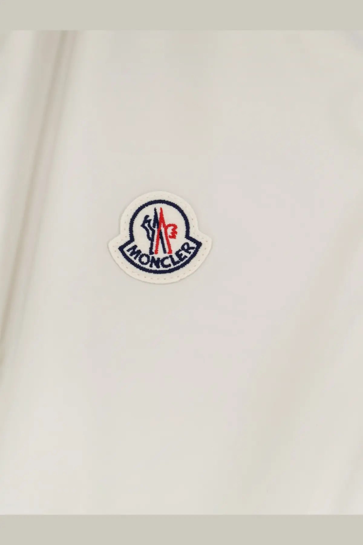 White moncler hemmoor jacket patch with embroidered red blue and black details on light fabric