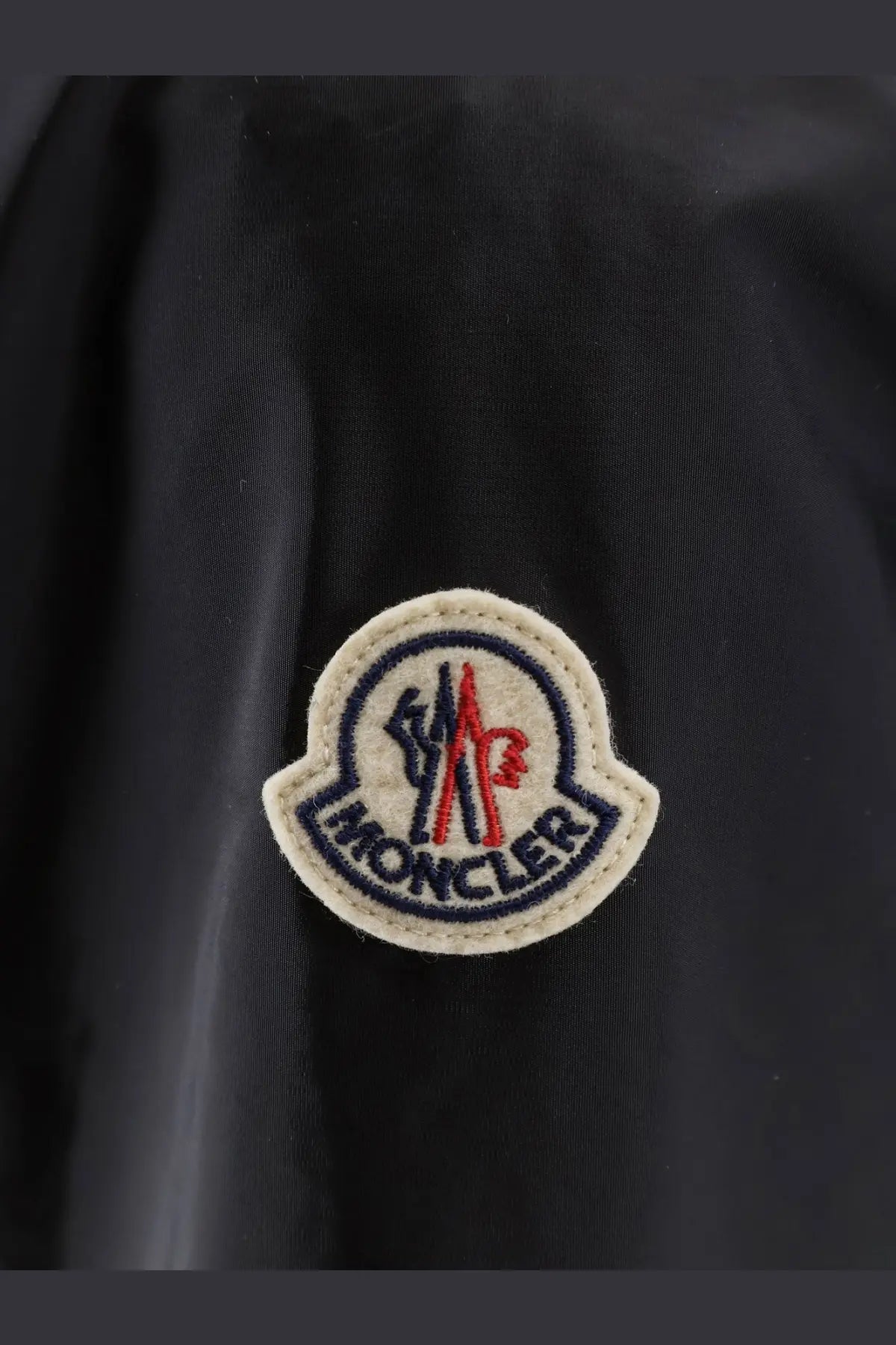 Moncler men’s nidge jacket black featuring a circular embroidered patch with red white and blue detailing on the back