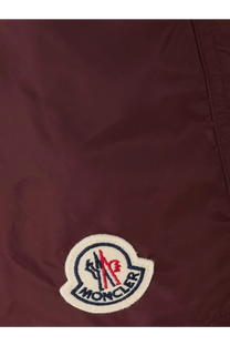 Maroon moncler logo patch with embroidered red black and white details on men’s brown nylon swim trunks