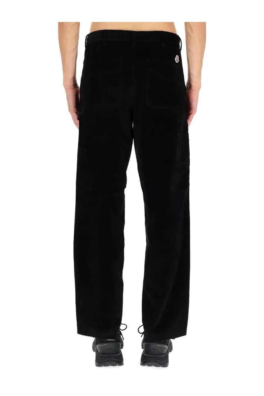 Back view of moncler men’s black ribbed corduroy pants with subtle texture and small white logo on back right pocket
