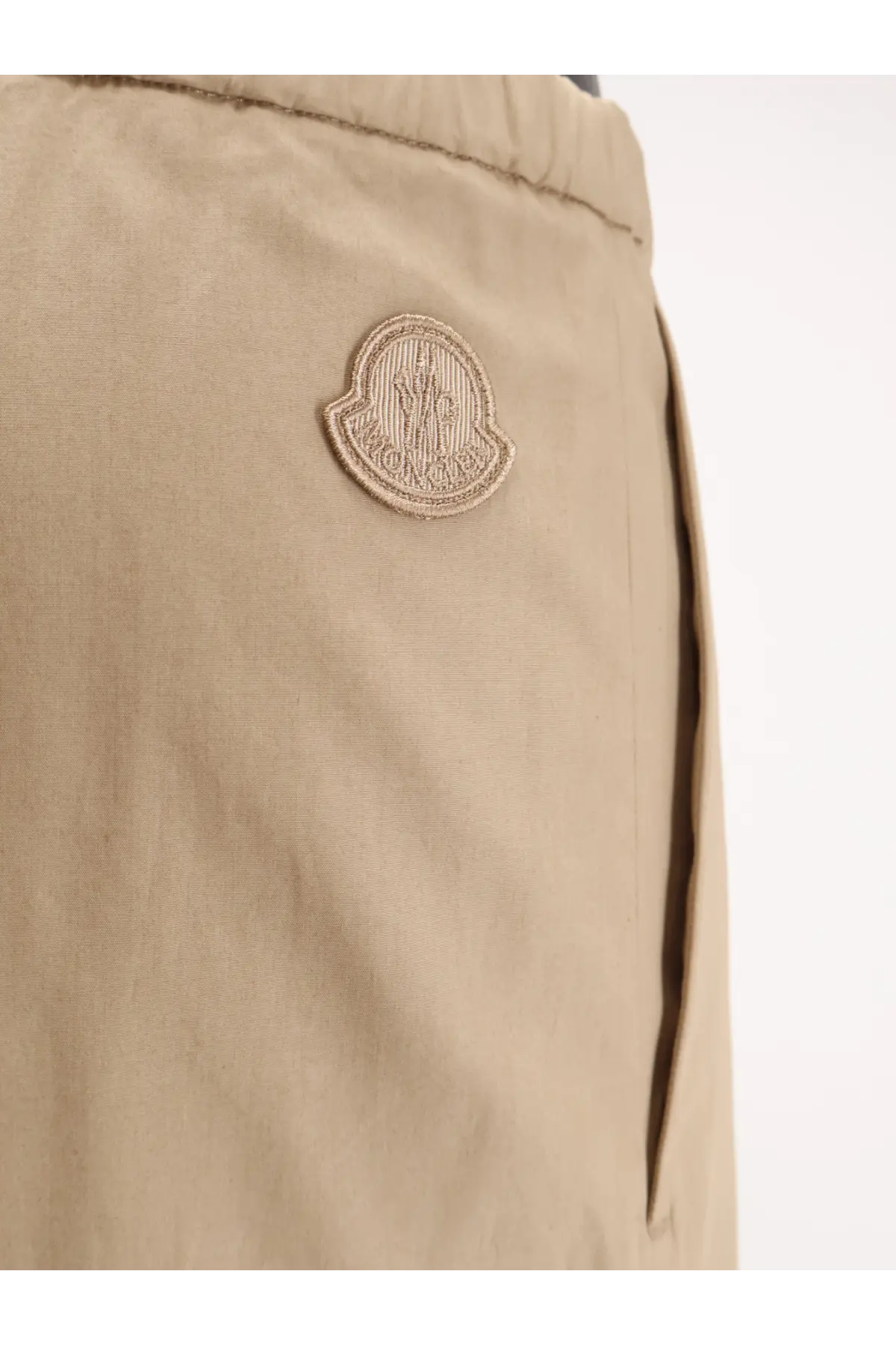 Beige moncler logo patch on khaki cotton fabric of moncler women’s cotton trousers front side
