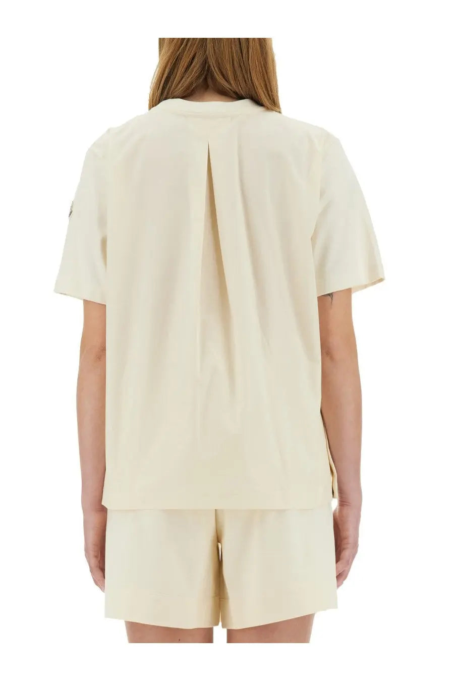 Back view of moncler women’s cream-colored short-sleeved shirt with central slit and subtle pleats