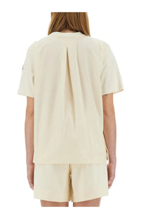 Back view of moncler women’s cream-colored short-sleeved shirt with central slit and subtle pleats