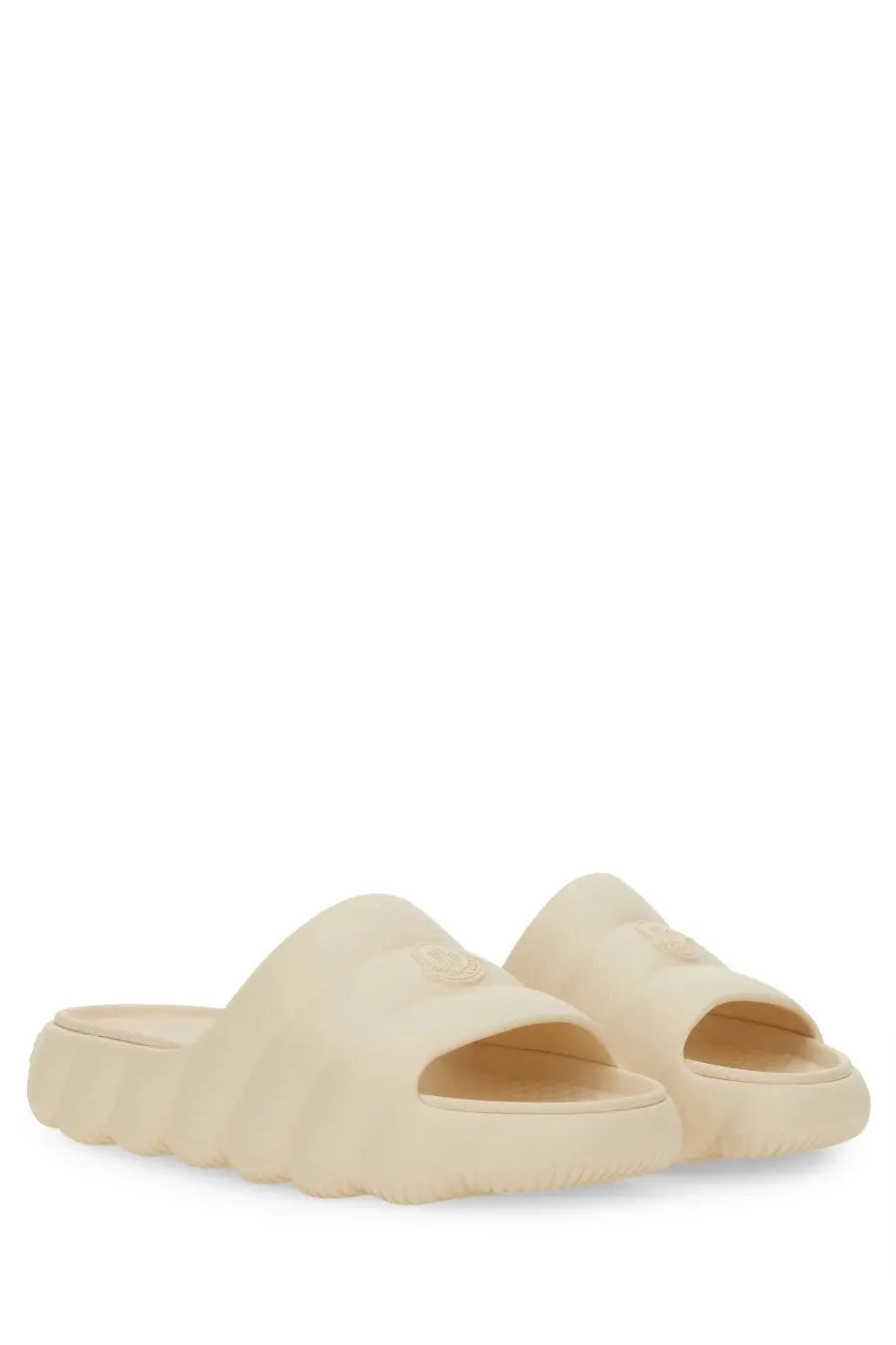 Cream-colored moncler women’s slide sandals made of molded rubber with a textured sole and subtle logo detail