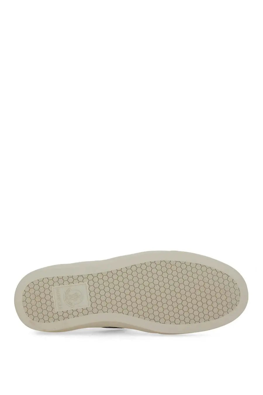 Beige rubber sole with hexagonal tread and rectangular brand label on the back of moncler womens white sneaker