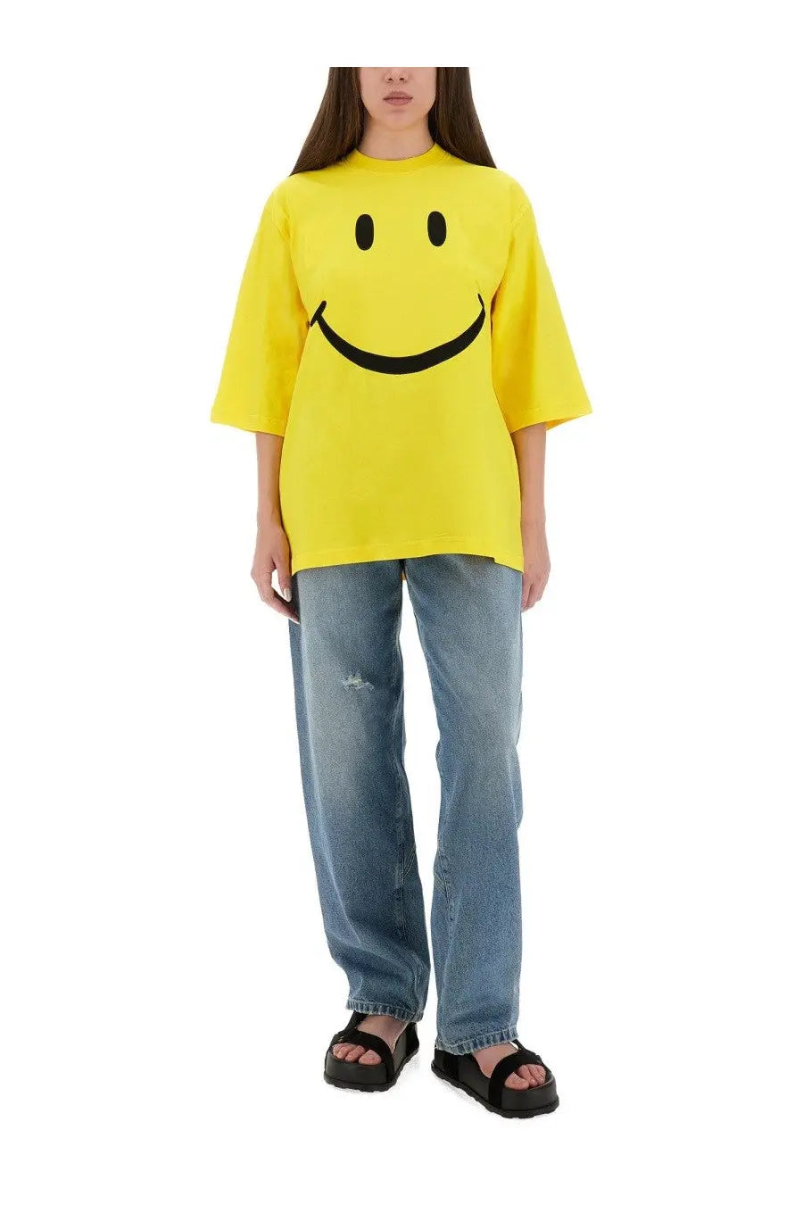Bright yellow oversized t-shirt with bold black smiley face graphic paired with moschino womens wide leg blue jeans