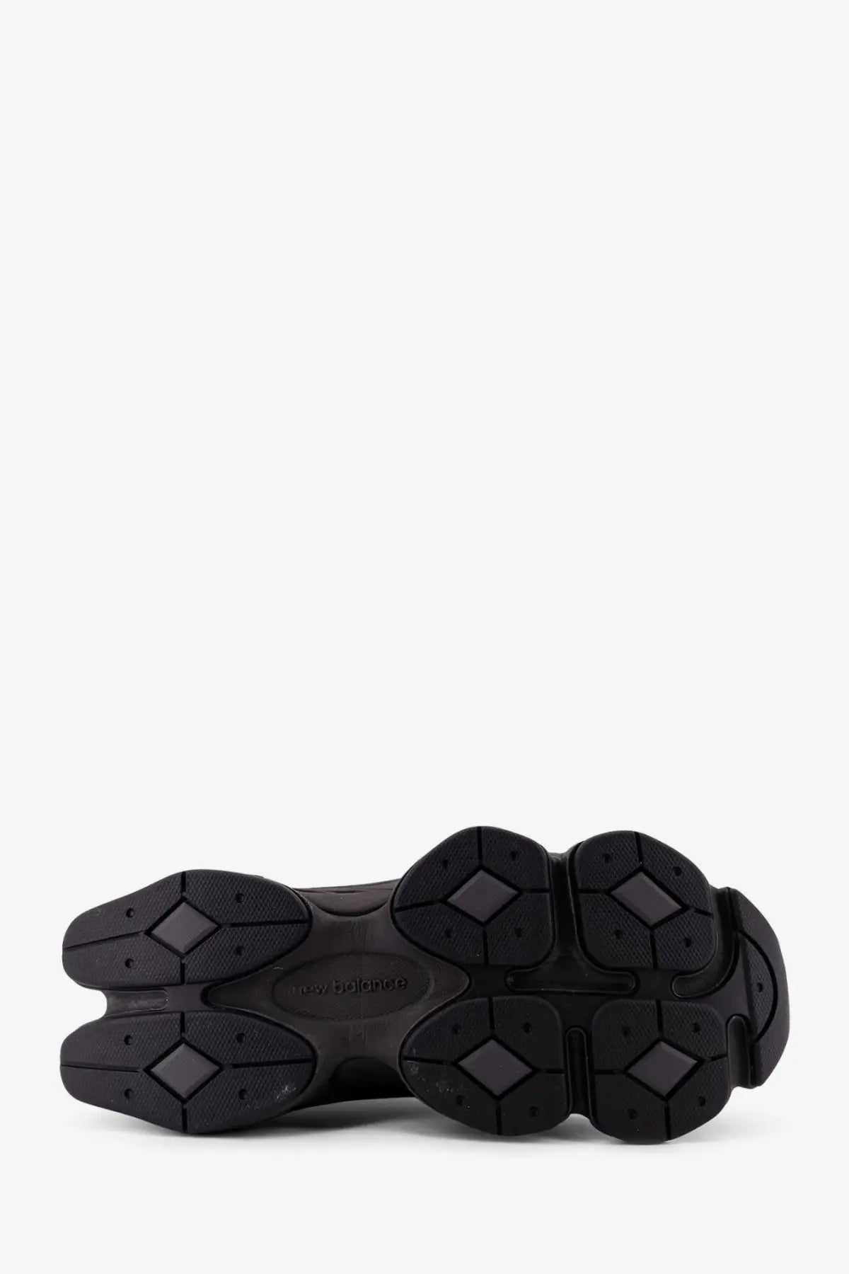 New Balance men’s black mesh sneakers featuring a black rubber sole with chunky multi-lobed design and embossed logo