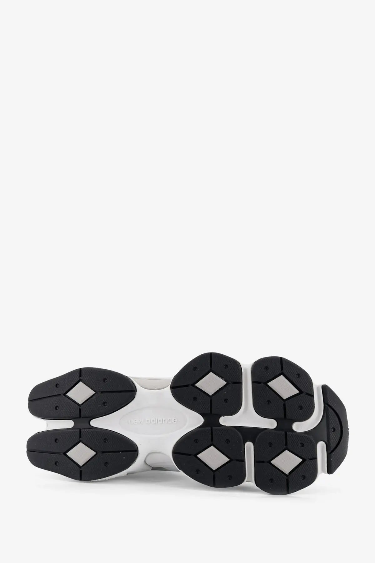 New balance men’s white mesh sneakers with black chunky sole and diamond-shaped rubber grips on the outsole