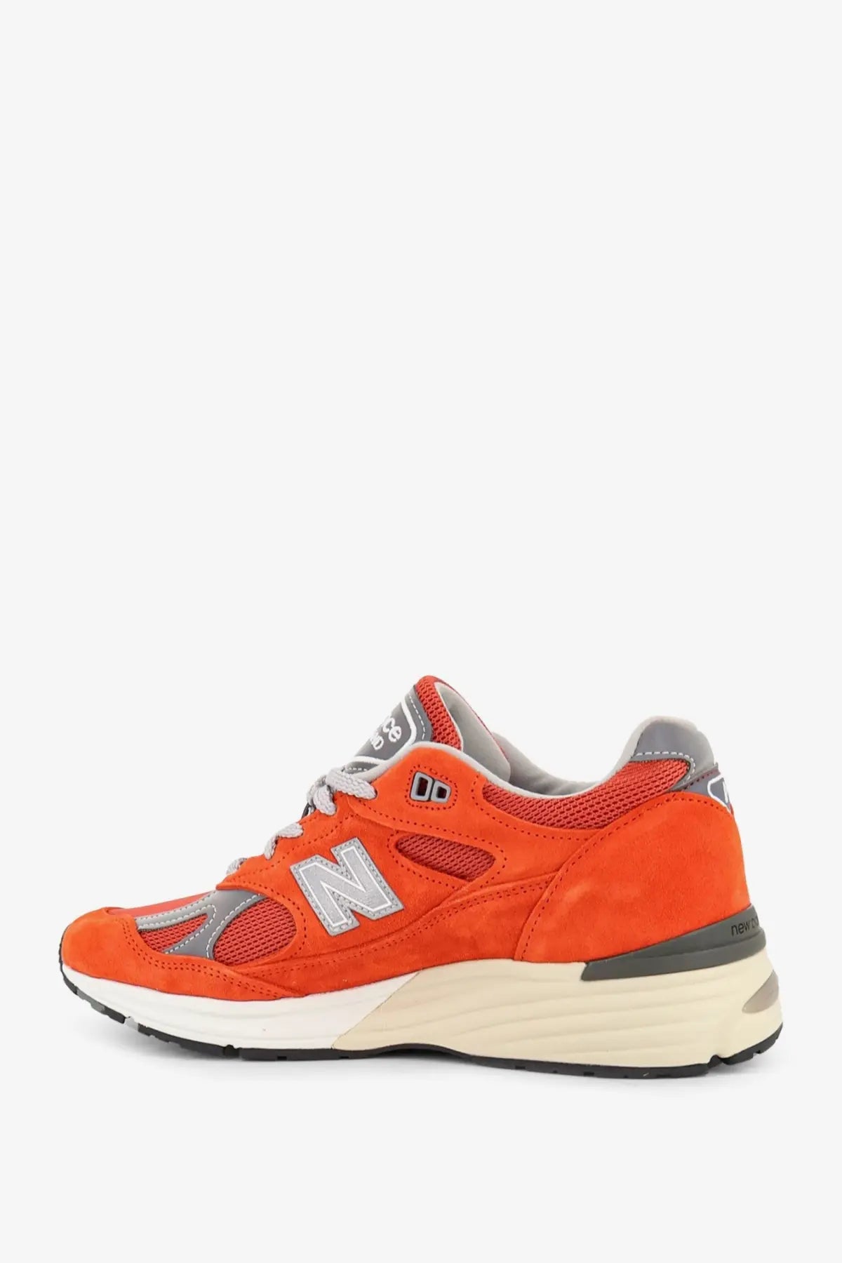 New balance men’s suede sneakers in vibrant orange with mesh and gray accents and a cream midsole