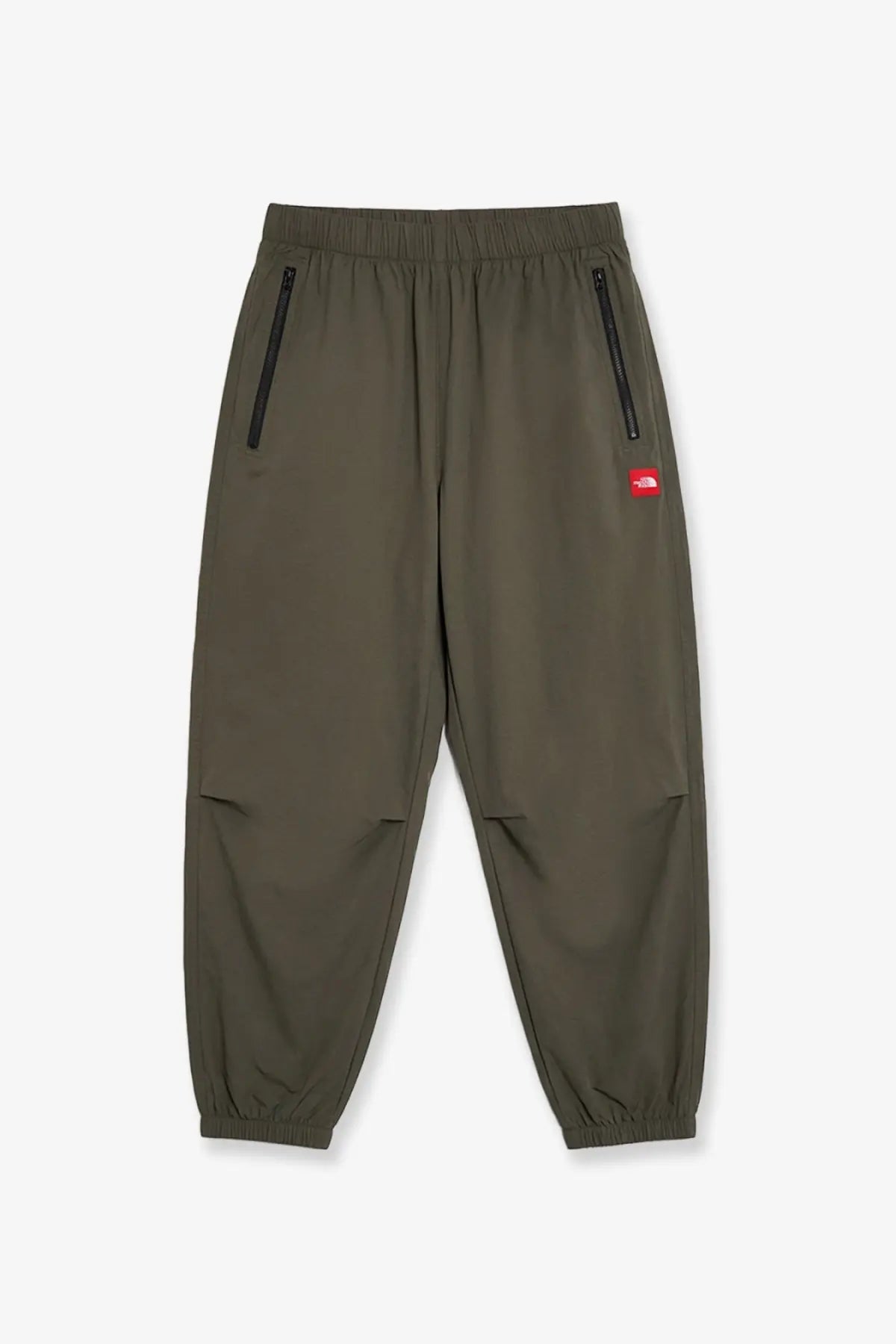 The north face men’s olive green nylon joggers with black zippers and a red brand patch on the thigh