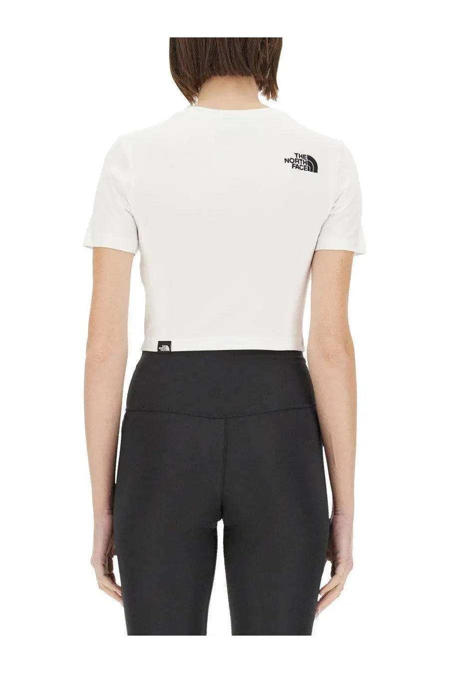 The North Face women’s white short-sleeved cropped shirt with black logo and minimalist design tag