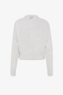 White cropped knit cardigan with long sleeves and central zipper paired with nude cotton blend polo shirt white