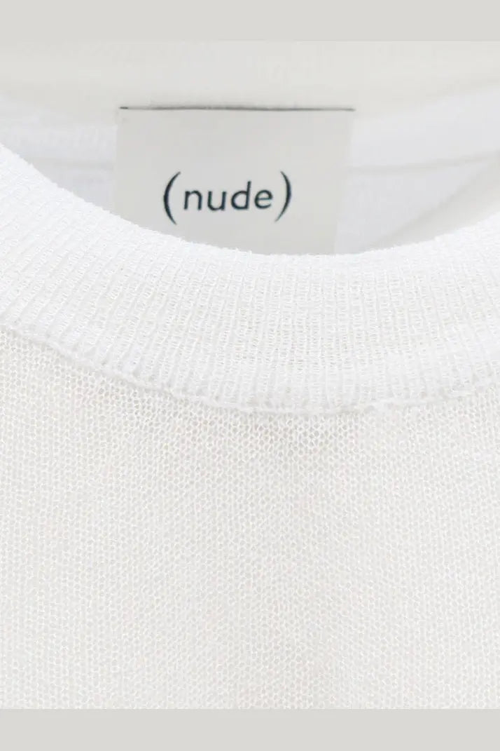 A minimalist white crewneck shirt in soft cotton blend knit fabric with a clean nude label on the front
