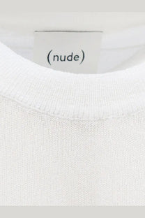A minimalist white crewneck shirt in soft cotton blend knit fabric with a clean nude label on the front