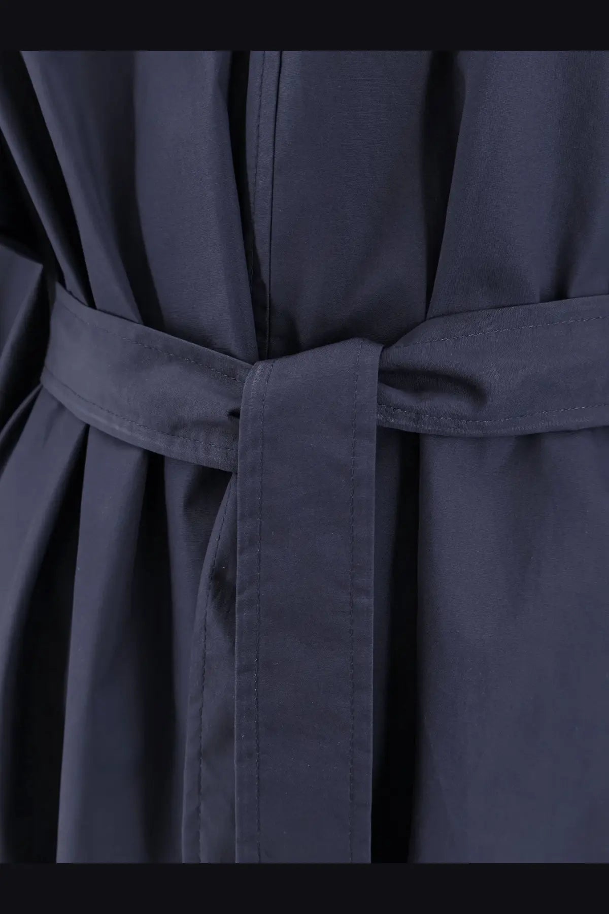 Dark navy belted coat with matching fabric belt tied in a neat knot over nude womens cotton dress blue