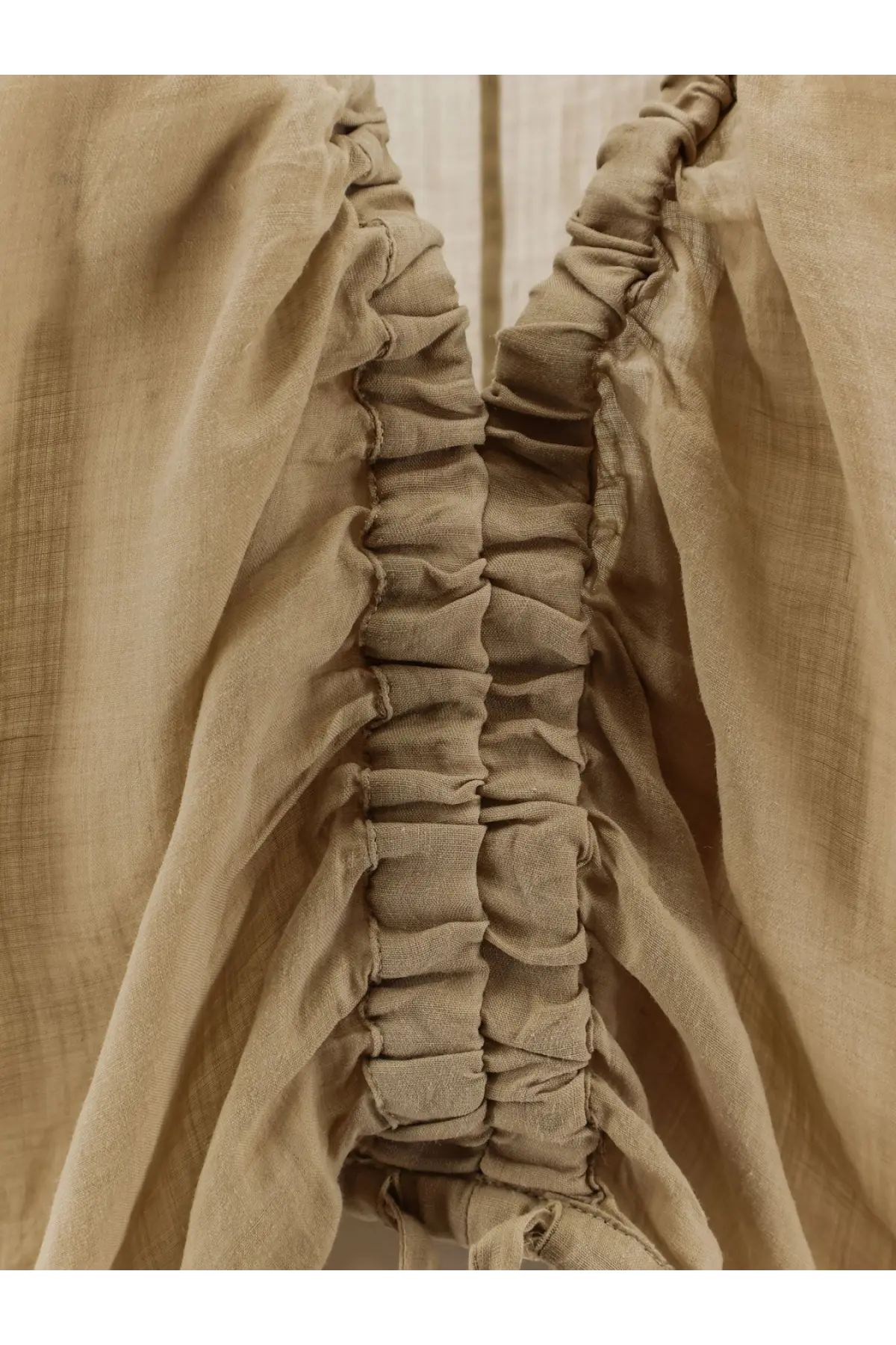 Nude women’s linen blend shirt in beige with gathered ruching along the side seam visible from the back side